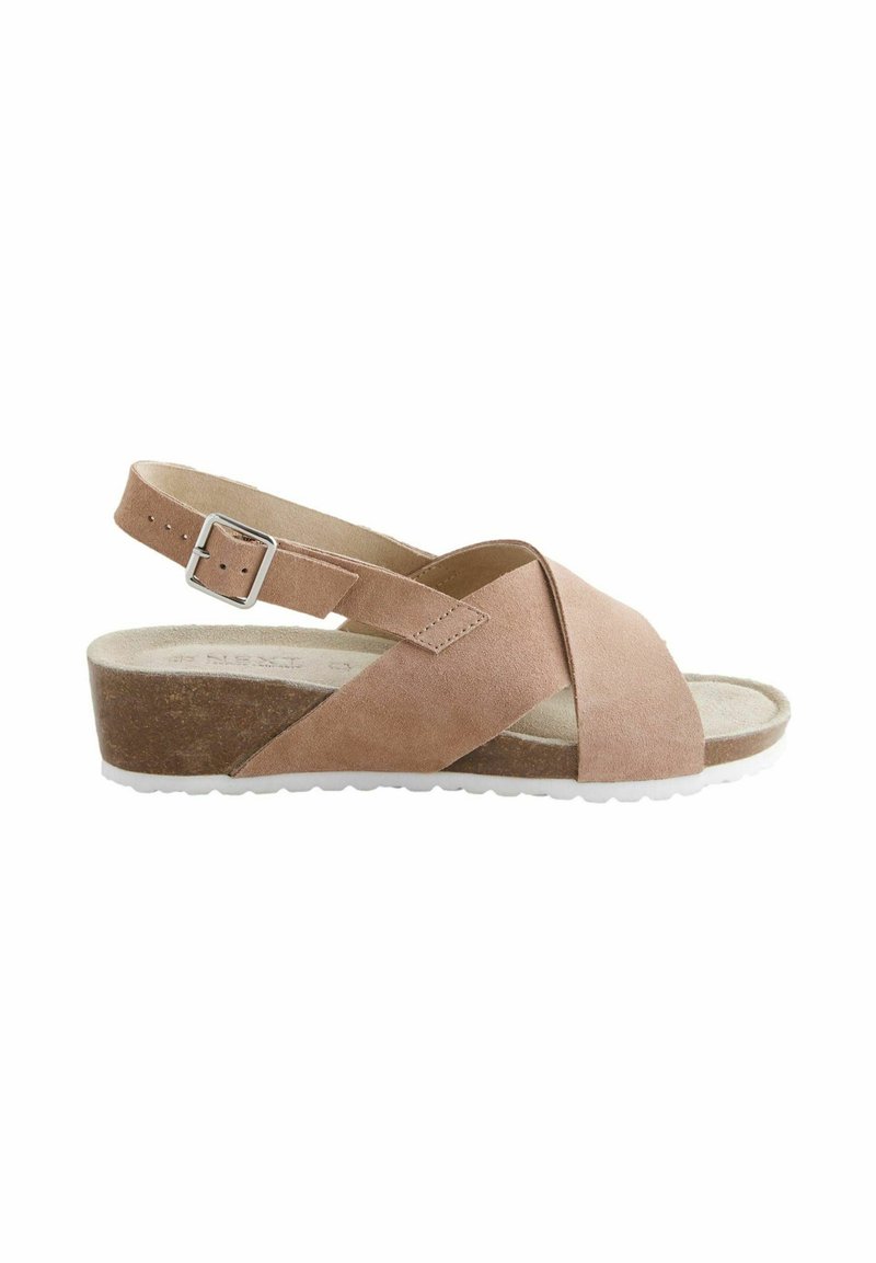 Sandale en suede marron avec des straps entrecroisés, une boucle ajustable à la cheville et une semelle en wedge basse. Semelle intérieure douce avec une surface texturée.
