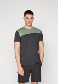 T-shirt da uomo in nero con pannello verde sulla spalla. Maniche corte, collo rotondo, realizzato in tessuto traspirante, con dettaglio del logo.