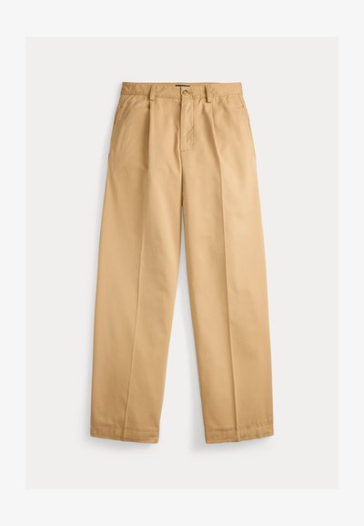 Beige vide bukser i bomullstoff, med folder foran, beltehemper og knappelukking i livet, samt sidelommer.