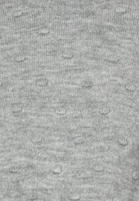 Gray knitted sweater with a textured pattern of raised dots, crew neckline, and ribbed edges. Soft material with a consistent finish.