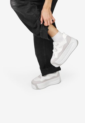Zapatillas de plataforma blancas y gris claro con un material de malla y suave, que presentan cordones, punta redondeada y acentos texturizados.