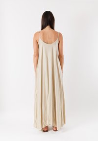 Abito maxi beige senza maniche con vestibilità comoda, realizzato in tessuto morbido, caratterizzato da uno scollo a barca e una silhouette fluida.