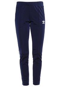Námořnické modré sportovní kalhoty s elastickým pasem a šňůrkou, s bílými bočními pruhy a kapsami na zip. Měkká, hladká tkanina.