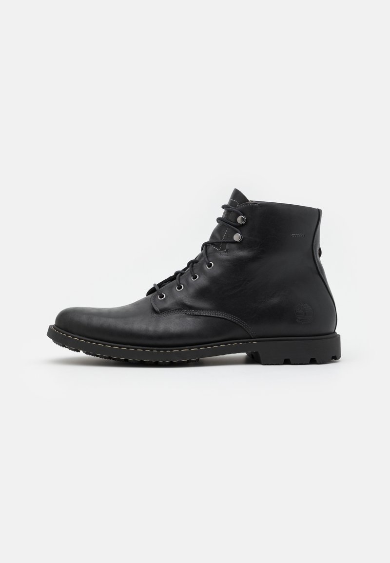 Bottine noire en cuir avec laçage à l'avant, œillets en métal, semelle robuste et logo embossé sur le côté du talon.