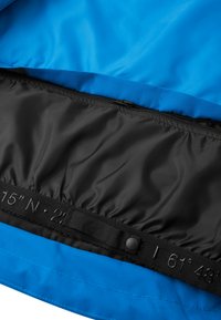 Interno della giacca blu con fodera nera e chiusura a zip. Include una fascia elastica e le coordinate geografiche stampate sull'orlo.