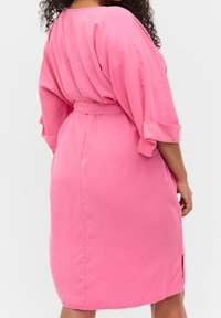 Różowa sukienka z paskiem, z krótkimi, podwiniętymi rękawami, gładką teksturą, bocznymi rozcięciami i luźnym krojem, z plisowanym tyłem.