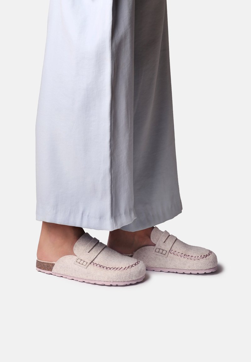 Chaussons en feutre gris clair avec une surface texturée, des coutures décoratives et une semelle en liège. Design à l'arrière ouvert pour un enfilage facile.
