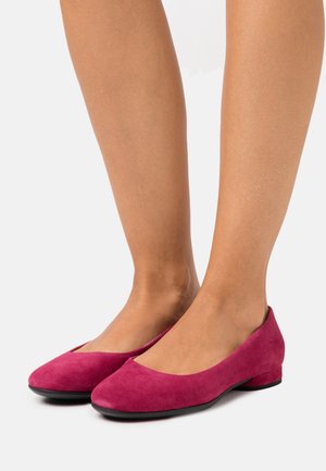 Ballerines en daim fuchsia avec une pointe arrondie, un petit talon et une texture lisse, présentant un design simple et minimaliste.
