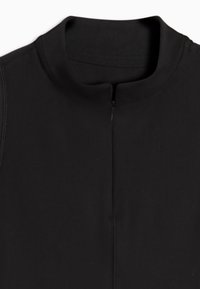 Μαύρο ένδυμα με κοντό φερμουάρ στο κέντρο μπροστά και στρογγυλεμένο λαιμόκοψη με μικρό όρθιο γιακά.