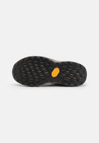 Semelle de chaussure avec une surface en caoutchouc noir et un motif de semelle distinct. Présente un logo hexagonal jaune au centre et des grips texturés pour une meilleure traction.