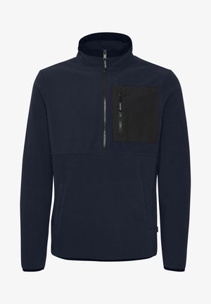 Navy fleece pullover with a high collar, half-zip front, and small black chest pocket. Features a soft texture and two side pockets.