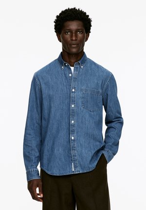 Hellblaue Jeanshemd im Button-Down-Stil mit einer Brusttasche und langen Ärmeln. Verfügt über eine glatte Textur und einen strukturierten Kragen.