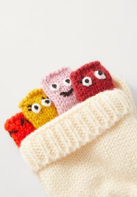 Strick-Aufbewahrungstasche in Creme mit vier bunten Plüschfiguren: rot, pink, gelb und orange, jede mit Augen und einfachen Gesichtsausdrücken.
