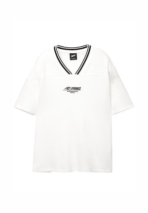 Biała krótka koszulka z dekoltem w kształcie V i czarnym podwójnym paskiem przy kołnierzyku, z napisem "ARTSPRINGS ATHLEISURE DPT. SINCE 91" wyśrodkowanym z przodu.