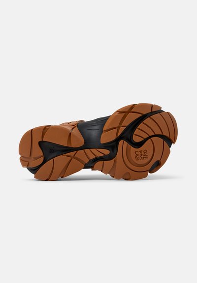 Sneaker-Außensohle mit einer schwarzen Gummibasis und einem braunen, strukturierten Profil. Auffällige Rillen und Muster verbessern den Grip und die Unterstützung.