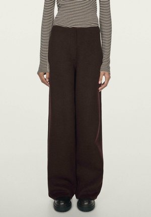 Spodnie o szerokich nogawkach w ciemnym bordowym kolorze, wykonane z miękkiej tkaniny, z wysokim stanem i gładką fakturą. Połączone z czarnymi butami na platformie.