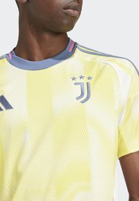 Gul sportströja med en texturerad design, med rund halsringning, grå accenter och Juventus-logotypen med tre stjärnor.