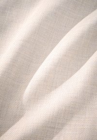 Tissu beige clair avec un motif chevron subtil ; texture lisse avec de légères plis. Idéal pour la tapisserie ou les vêtements.