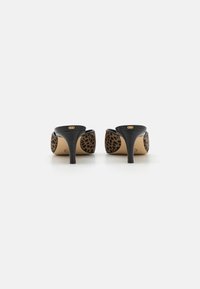 Mules à talons noirs avec des panneaux arrière en imprimé léopard, une texture lisse, des talons fins et des accents en or sur le talon.