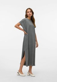 Szara, krótko rękawowa sukienka maxi z bocznymi rozcięciami. Gładki materiał, luźny krój, okrągły dekolt i minimalistyczny design. Zestawiona z białymi mulesami na obcasie.