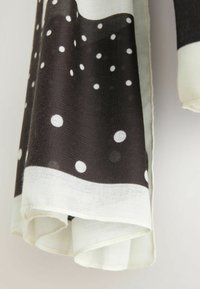 Czarnobiały szal z dużymi białymi grochami na ciemnym tle, z kontrastowym białym obszyciem i miękkim, teksturowanym materiałem.