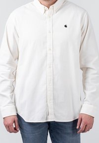 Witte button-up shirt van een gestructureerde, geribbelde stof. Voorzien van een klein zwart logo op de linkerborst. Lange mouwen met knopenmanchetten.