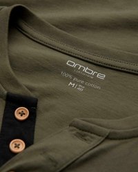 Olivgrön bomullsskjorta med en svart knappslå och två bruna knappar, med "ombre"-märket och storlek M tryckt inuti kragen.