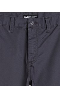 Un pantalon chino gris foncé avec fermeture à bouton, passants de ceinture et texture lisse. Comprend une étiquette de marque Vans au niveau de la taille.