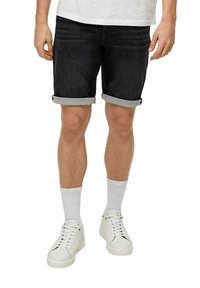Shorts en jean noir avec des ourlets retroussés, associés à des baskets blanches et des chaussettes ankle grises. Mettre l'accent sur la coupe décontractée et la texture du denim.