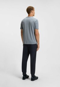 Kortärmad skjorta för män i ljusblått med rutmönster, i kombination med mörka smala byxor. Avslappnad passform med ribbade muddarna och rund hals.