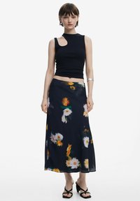 Sort sansærmet top med en udskæring på skulderen, parret med en flydende marineblå nederdel med et blomsterprint i hvidt og gult.