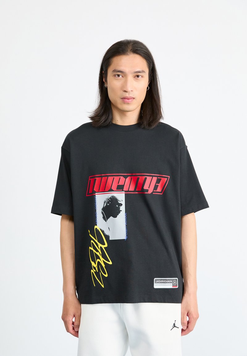 Black t-shirt with short sleeves featuring bold red and yellow graphics, a portrait silhouette, and a “Jordan” logo tag on the hem.