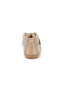 Zapato de ante beige con un tacón de cuero suave y un acento verde. Presenta un diseño de media caña y una suela de goma flexible para mayor comodidad.