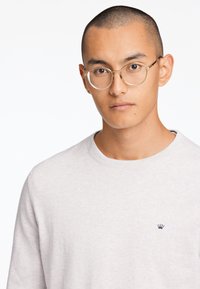 Lichtgrijze sweater gemaakt van zachte stof, met een ronde hals en een klein kroonlogo op de borst. De pasvorm is ontspannen met lange mouwen.