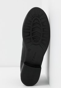 Semelle de chaussure noire avec un motif de crampons profond, taille 37 embossée, marque "s.Oliver", talon avec de fines rainures horizontales pour l'adhérence.