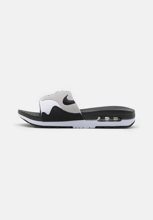 Sandale slip-on Nike noire et blanche avec semelle coussinée et unité Air visible au talon, affichée sur un fond clair uni.