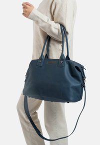 Marineblauwe leren handtas met dubbele handgrepen, verstelbare schouderband en zijdetails. Gladde textuur en subtiele stiksels.