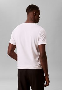 Λευκό βαμβακερό T-shirt με στρογγυλή λαιμόκοψη και κοντά μανίκια, με λεία υφή και χαλαρή εφαρμογή, από την πίσω όψη.