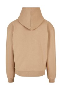 Felpa beige con tasca a marsupio, tessuto morbido, vestibilità comoda, polsini e fondo a coste, e cappuccio foderato. Design minimalista, senza branding visibile.