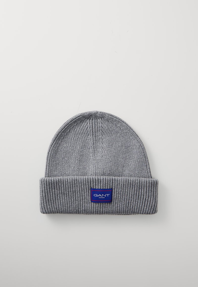 Gray knit beanie with a folded cuff. Features a blue rectangular label with white text on the front. Soft texture and ribbed design.