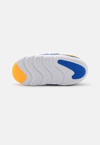 Suela de zapato con una superficie blanca texturizada y acentos en azul, amarillo y naranja. Diseño de banda de rodadura curvado para tracción y estabilidad.