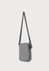 Γκρι ορθογώνια τσάντα crossbody με υφασμάτινο σχέδιο υφασμένου μοτίβου και ρυθμιζόμενο υφασμάτινο λουράκι σε λευκό φόντο.