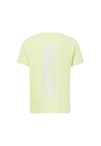 T-shirt kratkih rukava limun-žute boje od pamuka, s velikim bijelim natpisom "ALPHA INDUSTRIES" vertikalno na leđima.