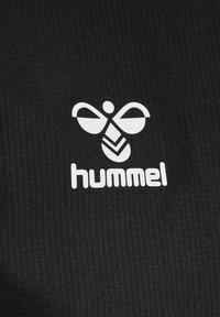 Tessuto nero con un motivo testurizzato, accompagnato da un logo bianco di un'ape stilizzata e la parola "hummel" sotto di essa.