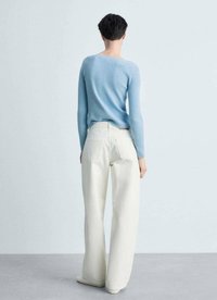 Maglione a coste blu chiaro con maniche lunghe, abbinato a jeans bianchi oversized a vita alta. Tessuto sottile e vestibilità sartoriale.
