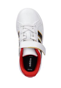 Białe sneakersy Adidas z czarnymi paskami, żółtym wykończeniem, czerwonym wyściełanym kołnierzem, sznurówkami i rzepem, widok z góry na białym tle.