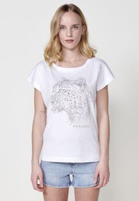 T-shirt blanc à manches courtes présentant un graphisme d'animal en pointillés et le texte "KÖROSHI" en bas, fabriqué à partir d'un matériau en coton doux.