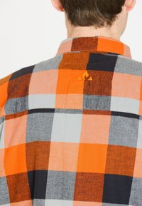 ternet skjorte med orange, grå og marineblå firkanter. Blødt stof med spredt krave og lille broderet logo på ryggen.