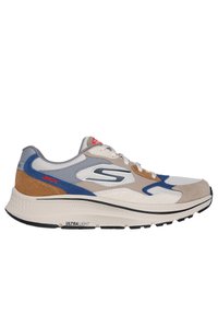 Sneaker léger avec un mélange de matériaux gris, marron et bleu, dessus texturé, semelle blanche et logo de marque visible sur le côté.