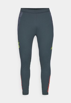 Pantaloni sportivi fitted di un grigio scuro con una texture liscia; presentano pannelli laterali in rete, un logo verde neon e strisce rosse lungo la parte inferiore delle gambe.